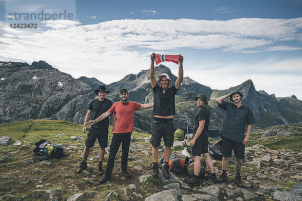 Norway  Lofoten  Moskenesoy  Group of young men cheering with Norwegian flag