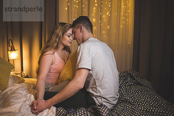 Romantic young couple sitting on bed