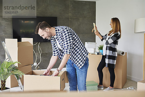Couple moving into new flat unpacking cardboard box