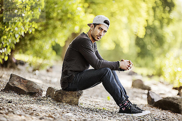 Portrait of young man with baseball cap sitting in nature