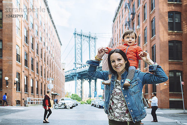 USA  New York  New York City  Mother and baby in Brooklyn with Manhattan Bridge in the background