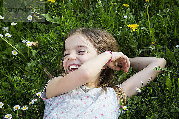 Portrait of laughing little girl lying on a meadow