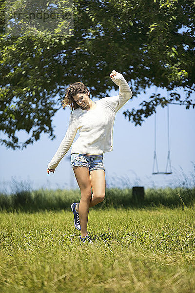 Young woman jumping around on meadow