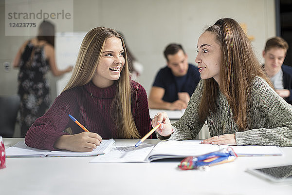 Smiling teenage girls talking in class