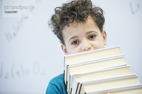 Portrait of schoolboy carrying books in class