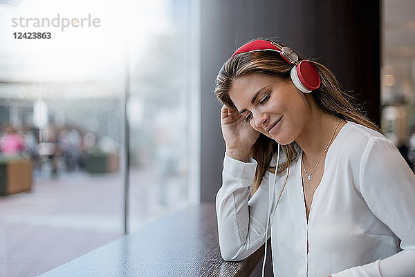 Smiling young woman listening to music with headphones