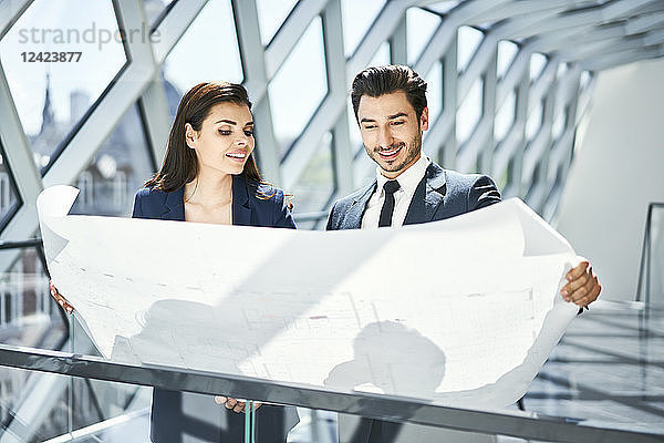 Smiling businesswoman and businessman looking at plan in office