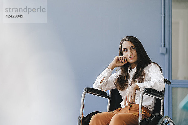 Young handicapped woman sitting in wheelchair  looking worried