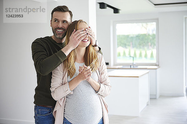 Man surprising pregnant woman in empty flat