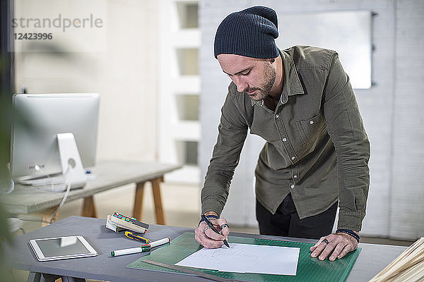 Young man taking notes at desk in office