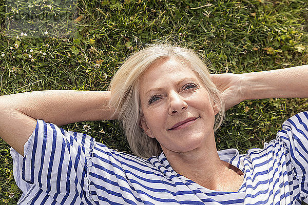 Portrait of smiling senior woman lying in grass
