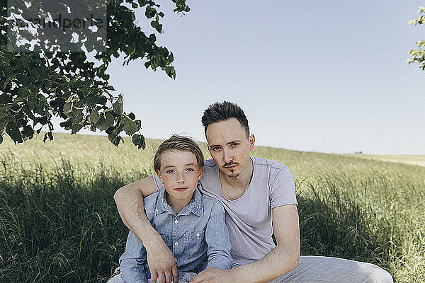 Portrait of young man embracing boy at a field