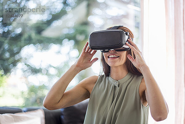 Smiling woman at home wearing VR glasses