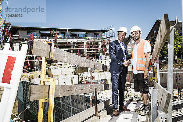 Man in suit shaking hands with construction worker on construction site