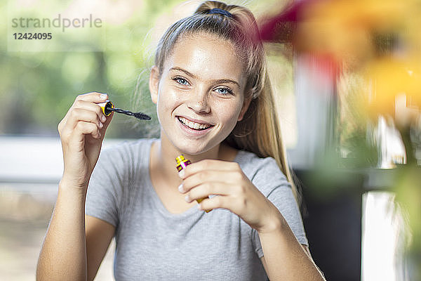 Portrait of smiling teenage girl applying makeup