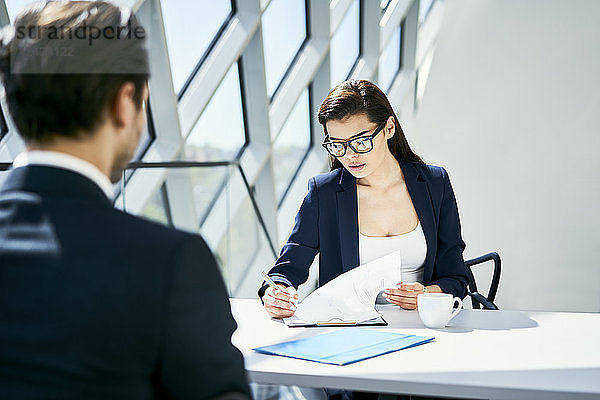 Businesswoman with businessman at desk checking documents in modern office