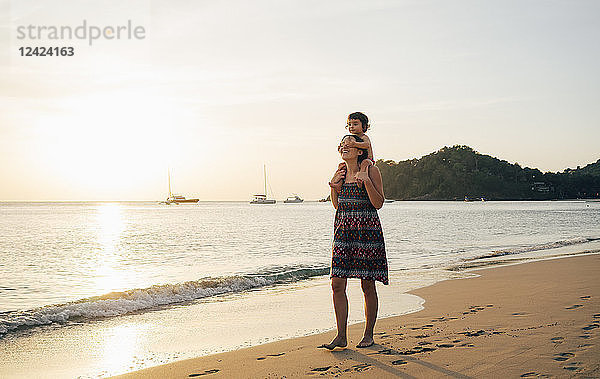 Thailand  Krabi  Koh Lanta  Mother with little daughter on her shoulders on the beach at sunset