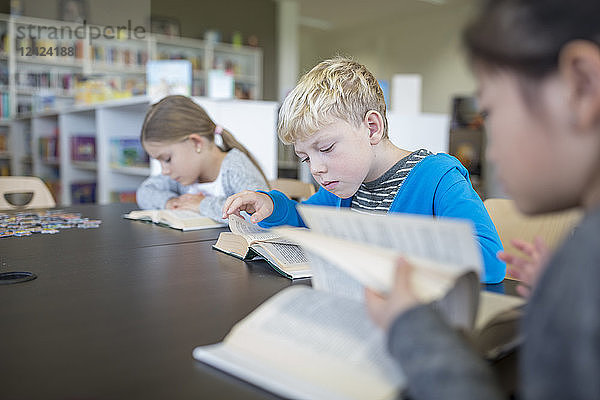 Pupils reading books on table in school break room