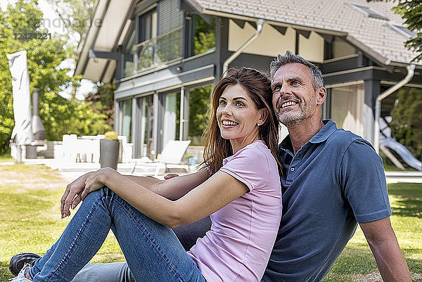 Happy couple sitting in garden of their home