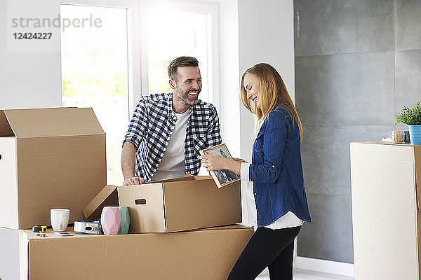 Couple moving into new flat packing cardboard boxes