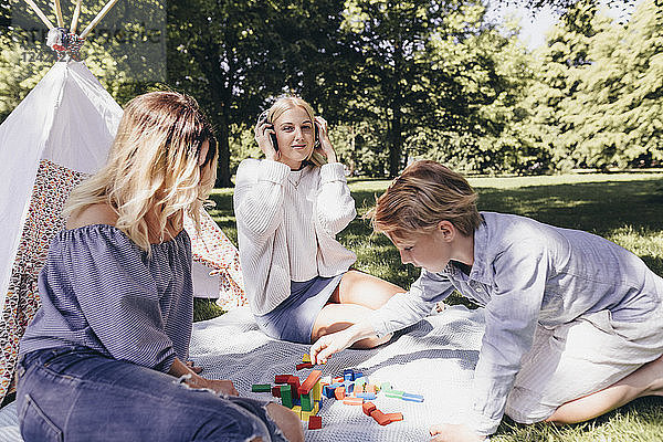 Two young women and a boy playing with building blocks in a park