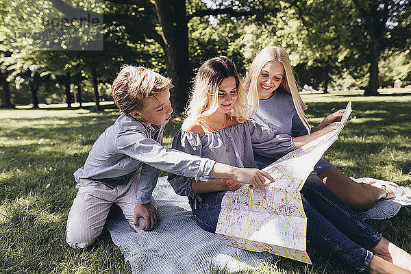 Two young women and a boy looking at map in a park