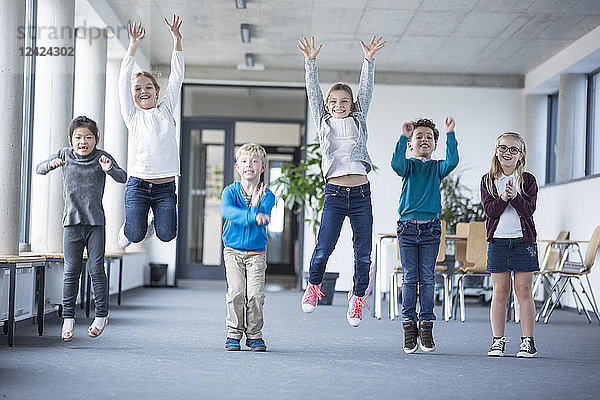 Excited pupils jumping on school corridor