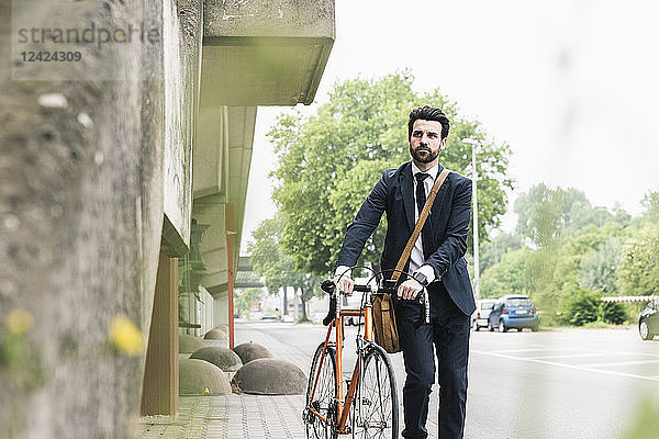 Businessman with bicycle walking at the street