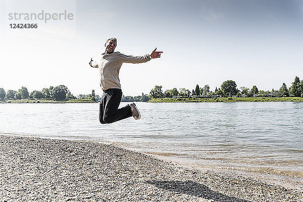 Mature man jumping in the air at Rhine riverbank