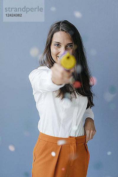 Pretty young woman shooting with a confetti gun