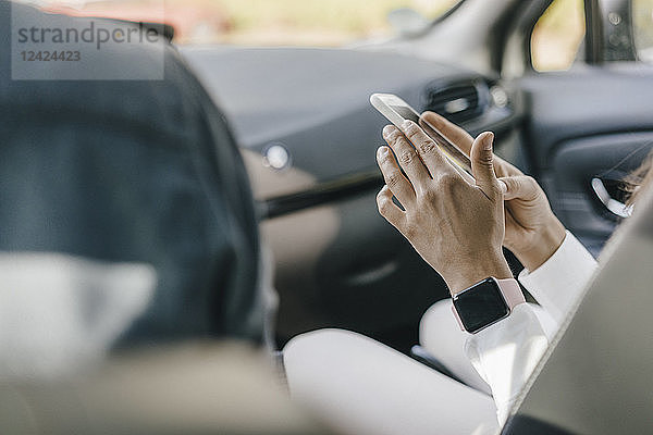 Young businesswoman sitting in car  using smartphone