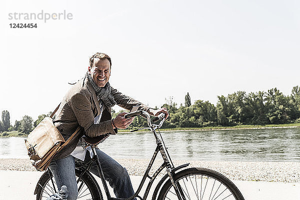 Mature man with bike using smartphone at Rhine riverbank