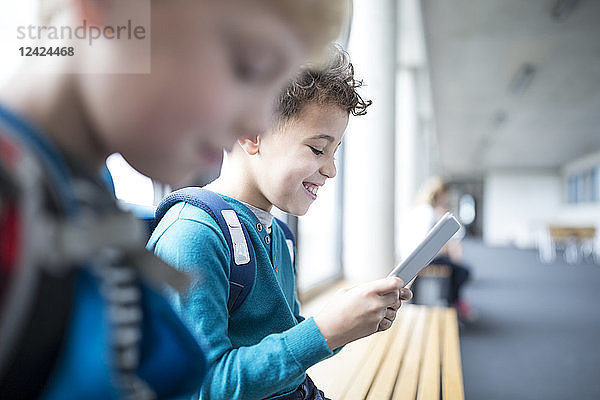 Smiling pupils with tablet on school corridor