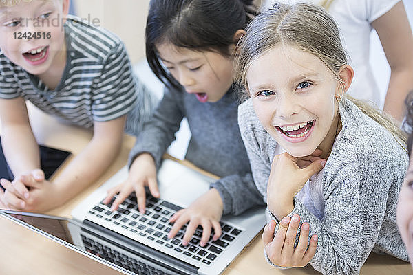 Happy pupils using laptop in class