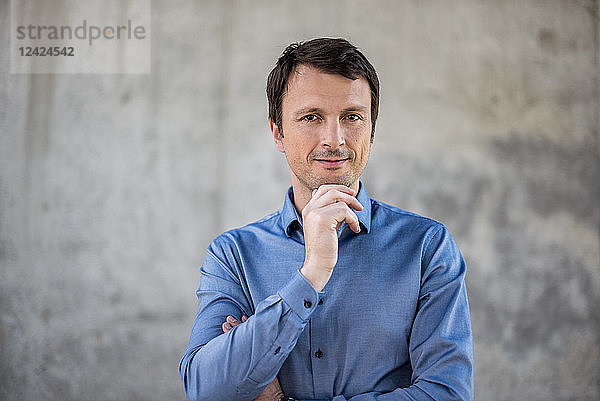 Portrait of confident businessman in front of concrete wall