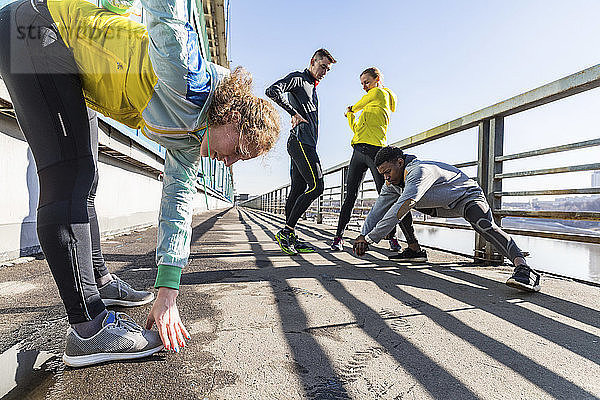 Friends doing stretching exercise on bridge in the city