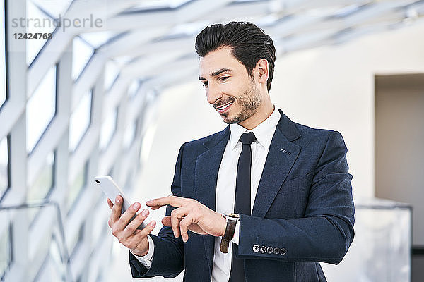 Smiling businessman looking at cell phone