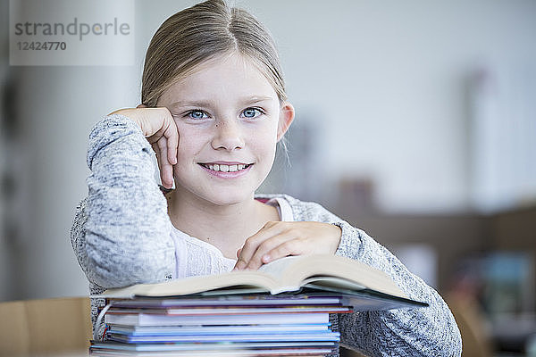 Portrait of smiling schoolgirl with books in school