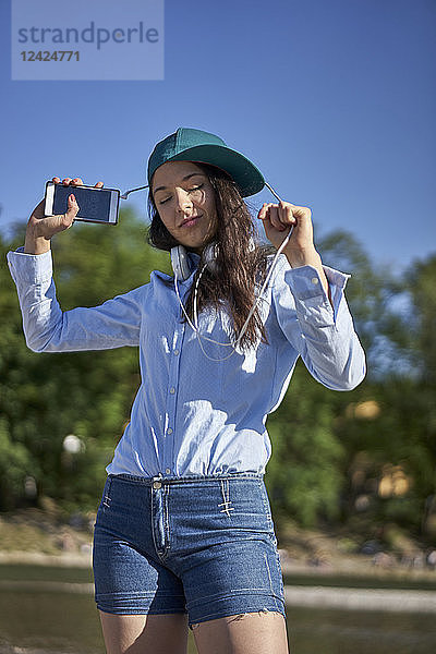 Portrait of dancing young woman with smartphone and headphones