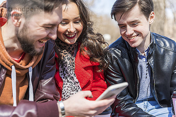 Russia  Moscow  group of friends at park  having fun together  using smartphones