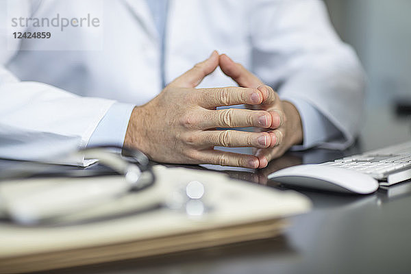 Files and stethoscope on desk in medical practice and doctor's hands