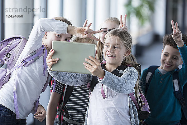 Happy pupils taking a selfie with tablet in school