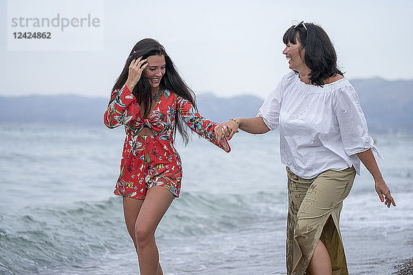 Greece  mother and adult daughter iwalking hand in hand at seaside