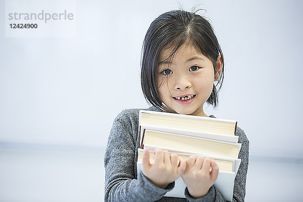 Portrait of smiling schoolgirl carrying books in class