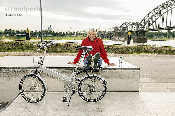 Smiling senior woman with city bike having a break