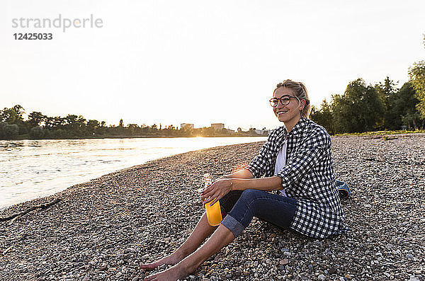 Blond woman sitting on riverside in the evening