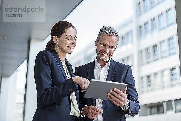 Portrait of two business partners looking together at tablet