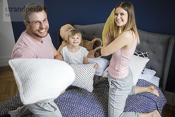 Happy family having fun in bedroom  having a pillow fight