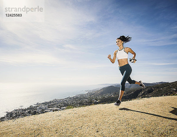 Frau joggt mit Wasserflasche auf einem Berg