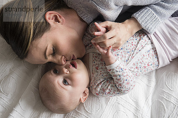 Mutter küsst liebevoll ihr kleines Mädchen (18-23 Monate)